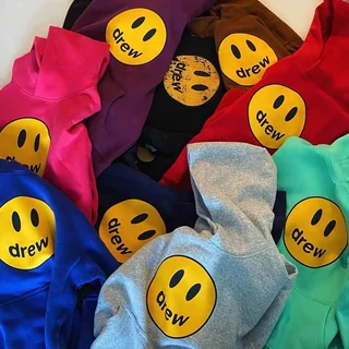 A heap of hooded sweatshirts in pink, blue, red, grey and green, each with a large yellow smiley print