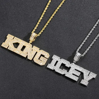 Two pendant chains on a dark surface, one gold and one silver, spelling out words in stone-set capital letters
