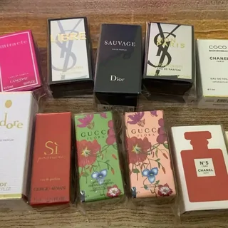 Perfume cartons and bottles of different shapes and colours laid out in rows on a wooden table